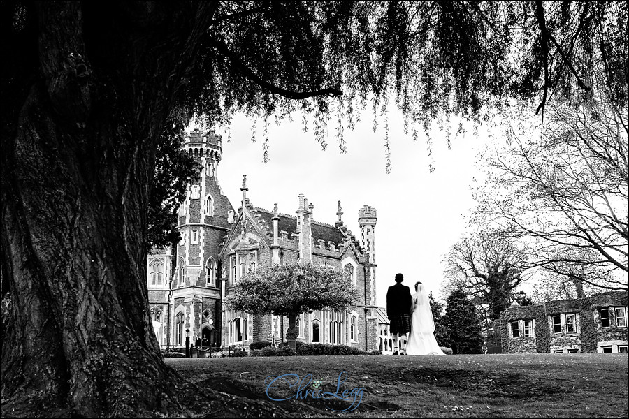 Black and white image of bride and groom standing outside Oakley Court Hotel