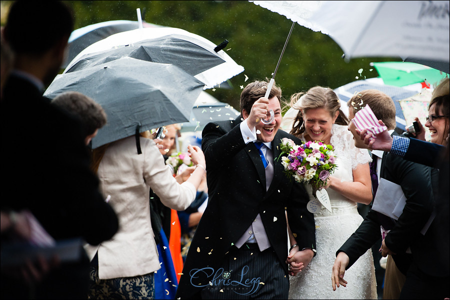 Bride and groom battle the rain as they leave the church