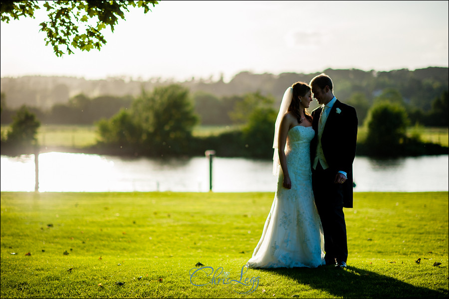 Bride and groom in the late afternoon sun by the Thames at Bisham Abbey